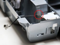 Klebeband entfernen: Das Kabel an der Ecke links vorne ist mit Klebeband am unteren Gehäuseteil befestigt.