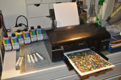 Der Drucker, die Tinte, Spritzen mit Kanülen zum wiederbefüllen und gerade frisch gedruckt die Farbfelder zum einmessen mittels des Spectralphotometers (i1 Pro von X-Rite)