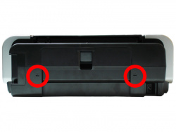 Um den Gehäuseteil vom Drucker zu trennen, muss man zunächst die beiden Clips hinten links und rechts mit einem Schlitzschraubendreher lösen.