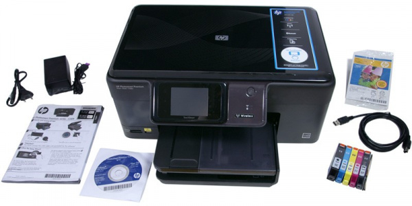 Lieferumfang HP Premium Photosmart C309g: Netzkabel, Netzteil, Handbuch, Treiber-CD, Tintenpatronen, USB-Kabel und ein Probepack Fotopapier.
