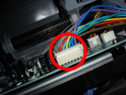 Damit das Druckwerk schließlich angehoben werden kann, muss man den Stecker des Netzteils an der Hauptplatine abziehen.