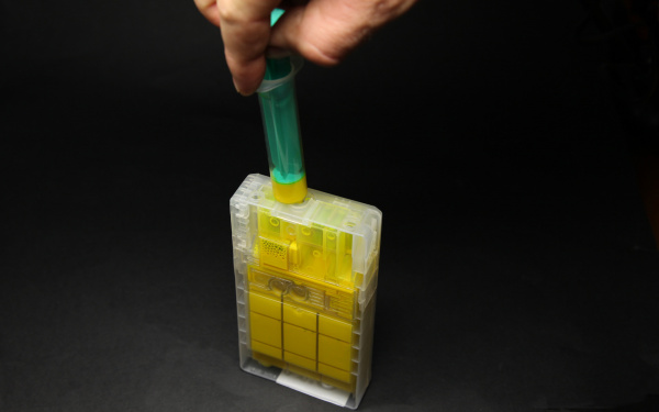 Entlüften II: Stecken Sie die Spritze (ohne Nadel) fest in die Tintenauslassöffnung und ziehen Sie am Spritzenkolben, bis Tinte kommt.