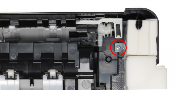 Festgeschraubt: Lösen Sie die markierte Schraube, welche die Plastikbox an der Bodeneinheit des Druckers fixiert.