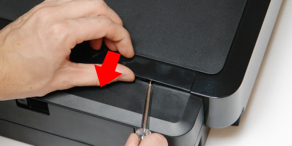 Zierleiste entfernen: Schieben Sie einen Schraubendreher in die Aussparung, drücken Sie damit den Clip etwas nach unten und ziehen Sie die Zierleiste gleichzeitig vom Drucker weg.