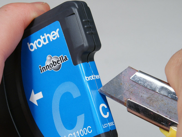 Aufkleber anritzen: Verwenden Sie ein Teppichmesser, um den Aufkleber an dieser Stelle anzuritzen.