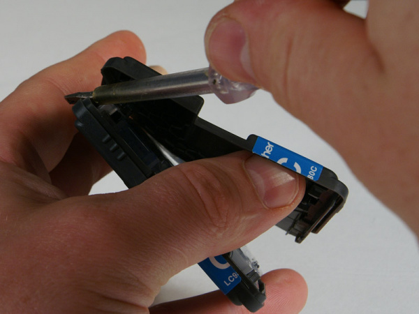 Aufhebeln 5: Auf der gegenüberliegenden Seite sind zwei weitere Clips. Hebeln Sie diese ebenfalls mit dem Schraubendreher vorsichtig aus.